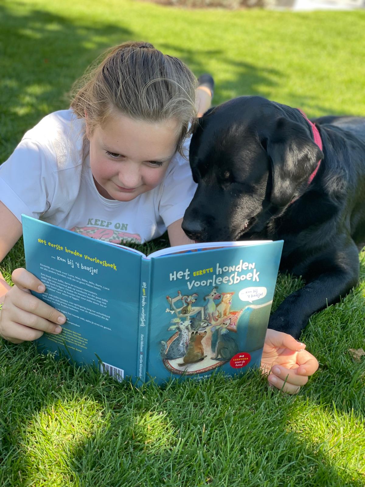kind leest met hond in het gras
